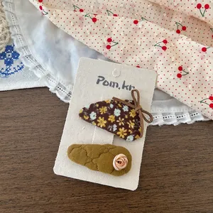 Détail de barrettes à fleurs et tissu matelassé avec petite rose sur carte support