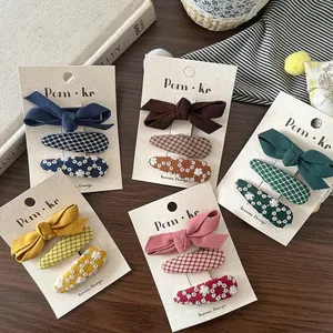 Cinq lots de barrettes brodées avec nœuds et motifs marguerites sur fond de bois naturel