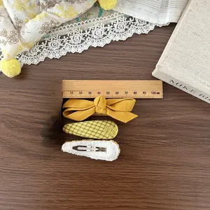 Détail d'un nœud en velours jaune et d'une pince à cheveux verte avec règle de mesure