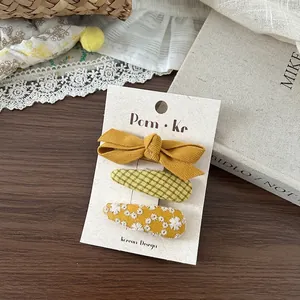 Lot de trois barrettes brodées de fleurs style coréen présentées sur un fond bois rustique