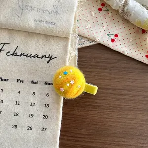 Detail of yellow wool felt hair clip with colorful stars and pearl on wooden background