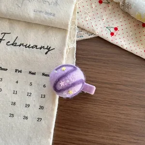 Detail of purple handmade wool felt planet hair clip with stars and pearls on wooden desk