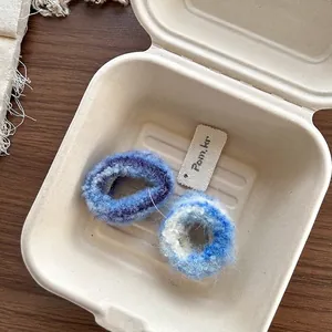 Détail de deux chouchous en tricot pelucheux aux motifs tie-dye bleus et violets