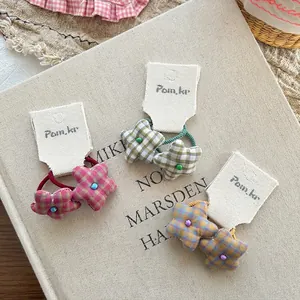 Three sweet plaid star fabric hair ties in pink, green, and yellow on cream card display