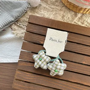 Detail of green plaid star hair ties for girls on a rustic wooden tray with a warm background