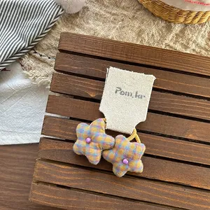 Detail of yellow and blue plaid star fabric hair ties with purple bead on a display card