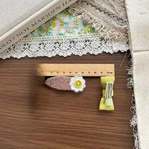Dettaglio di fermaglio in tweed con fiori ricamati e fiocco verde su libri antichi