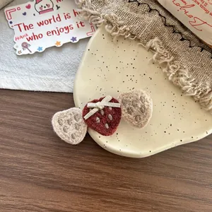Détail de barrettes fraises tricotées à la main avec nœud sur assiette rustique