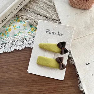 Dettaglio di due fermagli per capelli in tessuto fatti a mano con fiocchi marroni