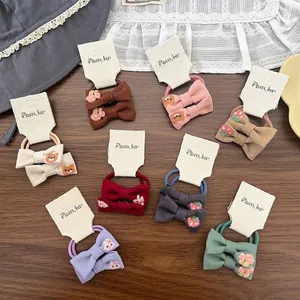 Cartoon embroidered bow hair ties for children in various colors on wooden surface