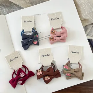 Close-up of bow hair ties with cute strawberry and bear embroidery on fabric surface