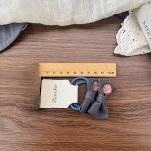 Detail of dark grey bow hair ties with strawberry embroidery and blue elastic band