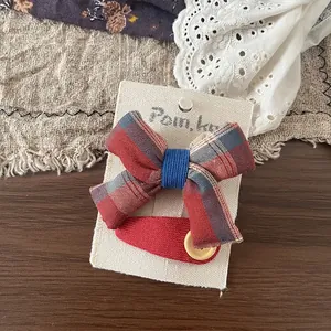 Détail d'un nœud papillon en tissu à carreaux et d'une pince rouge sur une carte