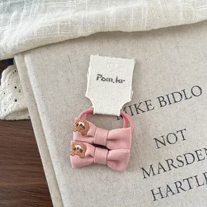 Pink bow hair ties set with cute bear embroidery on a decorative rustic background