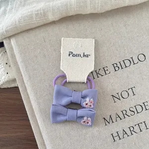 Detail of purple fabric hair ties with cute rabbit embroidery on beige textile tags
