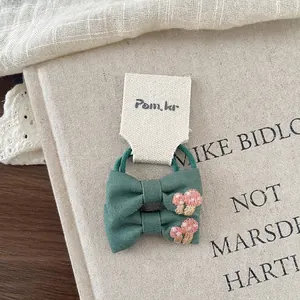 Detailed view of two dark green linen bow hair ties with cute mushroom embroidery