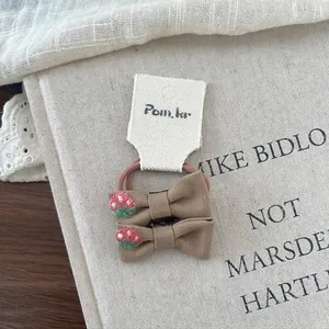 Detail of linen bow hair ties with strawberry embroidery and soft lace background