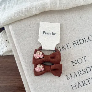 Detail view of brown fabric hair bows with cherry embroidery and high elastic bands