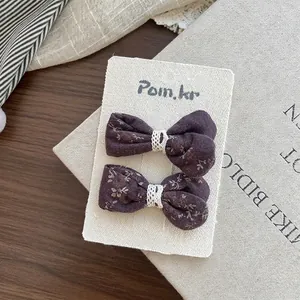 Dettaglio di due fermagli per capelli viola a fiori con pizzo su carta espositiva