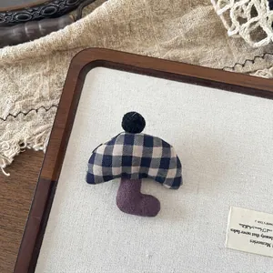 Close-up of blue plaid fabric umbrella brooch with black pompom on a linen tray