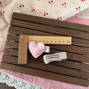 Set aus rosa und grauen karierten Herz-Haarspangen auf dekorativem Holzhintergrund