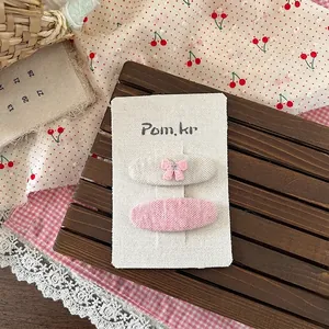 Detailansicht der Haarspangen aus Stoff mit rosa Schleifen auf einer weißen Karte