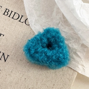 Détail macro d'une pince à cheveux en peluche bleue en forme de cœur, texture laine