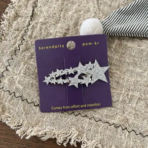 Makroaufnahme glitzernder silberner Pailletten-Sterne auf violetter Karte mit beigem Stoff
