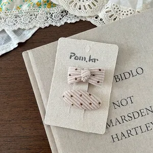 Detailaufnahme von cremefarbenen Cord-Haarklammern mit Punkten auf Vintage-Papier