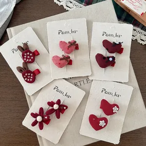 Simpatici fermagli per capelli in tessuto rosso con cuori e fiori su scheda display