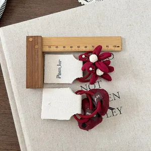Dettaglio di elastici per capelli in tessuto rosso per bambine su sfondo di lino