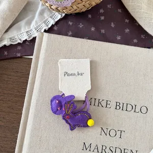 Nahaufnahme von lila Filz-Hasen-Haargummi mit gelbem Pompon und genähten Details