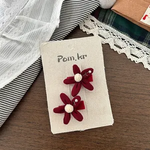 Vista dettagliata di fermagli per capelli a fiore rosso con perle per bambine