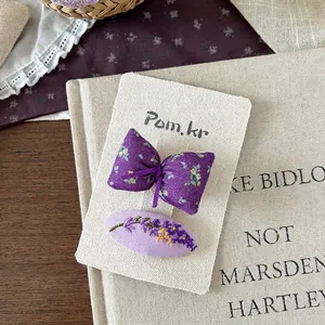 Detailansicht lila Stoffhaarnadeln mit Blumenmuster und Lavendel-Stickerei auf einer Karte