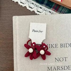 Dettaglio ravvicinato di elastici per capelli a fiore rosso scuro con perle e peluche
