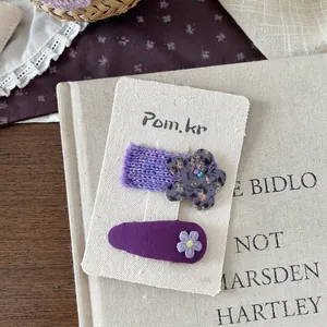 Detailansicht lila Stoff-Haarspangen mit besticktem Gänseblümchen und gestrickter Blume