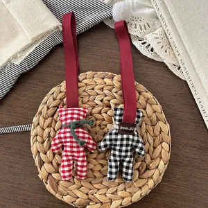Detail of red and black gingham fabric bear charms on a woven mat with vintage decor
