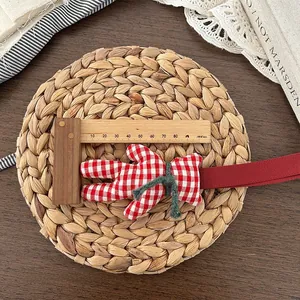 Detail view of handmade red and white checkered bunny charm with a green bow