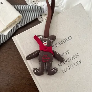 Detail of a brown fabric bear pendant with red scarf and embroidery on a vintage background