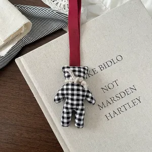 Close-up of black and white checkered fabric bear pendant with rustic red strap
