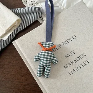 Detail of a green checkered plush bear with an orange scarf on a fabric book