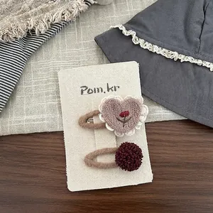 Detail der bestickten Herz-Haarklammer und Plüsch-Pompon für Kinder im Vintage-Stil