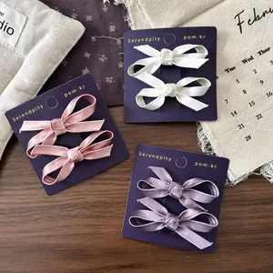 Three pairs of elegant bow hair clips in pink, white, and purple for girls on a card