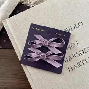 Detail of two lilac satin bow hair clips for girls on a premium purple display card