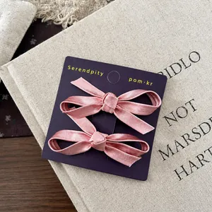 Detail of pink satin bow hair clips on a purple display card with silk texture