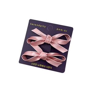 Set of two pink satin bow hair clips for girls on a professional purple display card