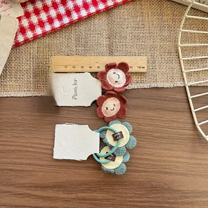 Detail von gestrickten Blumen-Haargummis mit Smileys und 40 mm Durchmesser auf Holzgrund