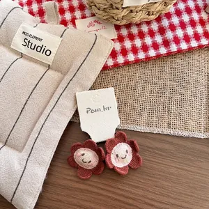 Nahaufnahme von gestrickten Blumen-Haarspangen auf weißer Karte mit Requisiten