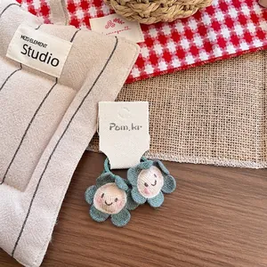 Detail von Häkelblumen-Haarschmuck mit gesticktem Smile-Gesicht auf einem Holztisch