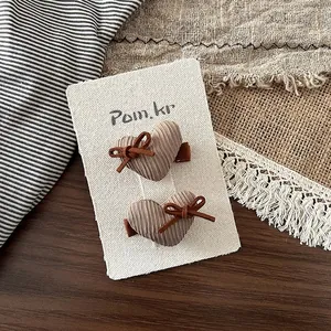Gros plan de pinces à cheveux en forme de cœur en velours côtelé marron sur carte de support